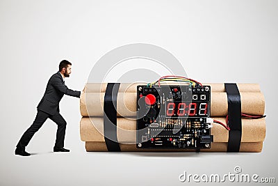 Small businessman in formal wear pushing big bomb Stock Photo