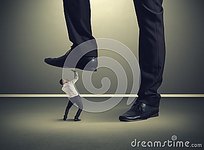 Small businessman under big leg Stock Photo