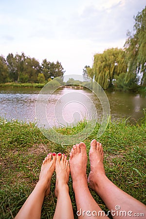 A small camping tent on the lake, a night`s lodging and the feet of a young couple Stock Photo
