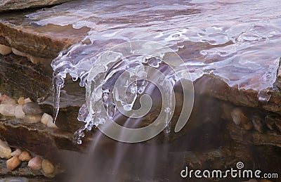 Icicles and flowing water on a waterfall Stock Photo