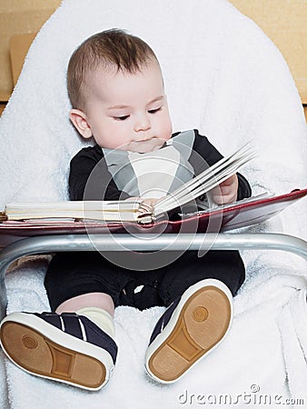 Small caucasian baby boy sitting in chear with notepad Stock Photo