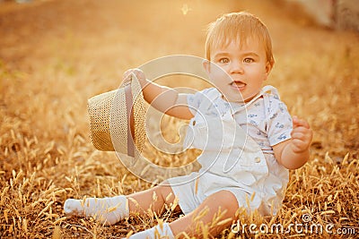 Small charming chubby little boy in a white suit holding a hat , Stock Photo