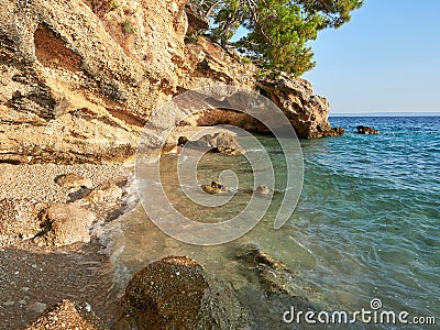 A small, charming pebble beach hidden under a cliff in the Croatian town of Brela. A cove on the shores of the Adriatic sea. Stock Photo