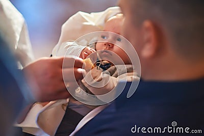 A small child at a baby christening ceremony in a church. the godfather holds a little boy in his arms. Baptism of a Stock Photo