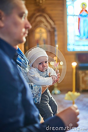 A small child at a baby christening ceremony in a church. the godfather holds a little boy in his arms. Baptism of a Stock Photo