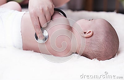 Small child, a baby, lies back at the doctor`s office and the doctor listens to the lungs, the heart Stock Photo