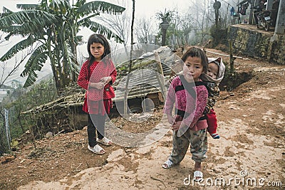 A small child in a bag behind a teenage girl. Red dzao - a small nation of North Vietnam Editorial Stock Photo
