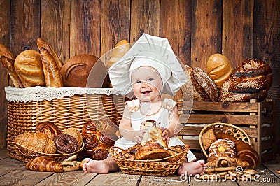 Small child cooks a croissant in the background of baskets with rolls and bread. Stock Photo