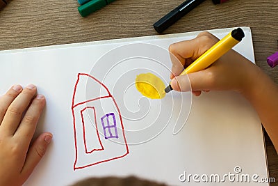 A small child draws a house with markers in the album. Step-by-step instructions Stock Photo