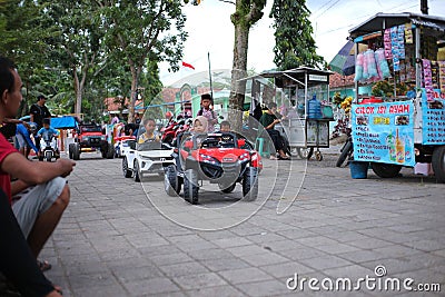 A small child driving a mini car that is controlled using a remote control by his parents Editorial Stock Photo