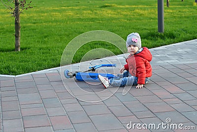 A small child fell from a scooter and is trying to climb, walking children in the park Stock Photo