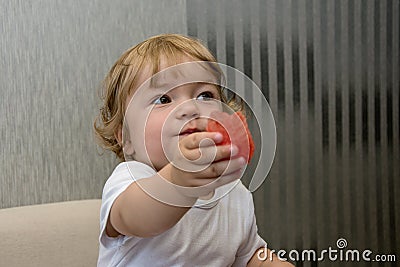 A small child holds out a piece of watermelon, treats people, generous person, children`s kindness Stock Photo