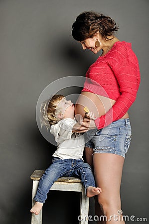 Small child holds a stomach of pregnant mother Stock Photo