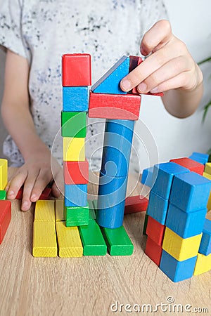 Small child, kid plays with colored wooden cubes, builds houses and rockets, the concept of the development of creativity, fine Stock Photo