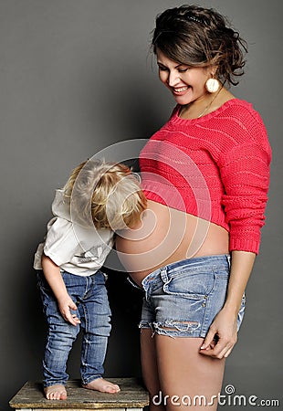 Small child kisses a stomach of pregnant mother Stock Photo