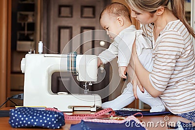 Small child learns new knowledge, along with his mother inspects sewing machine. Work at home, parenting, parents and Stock Photo