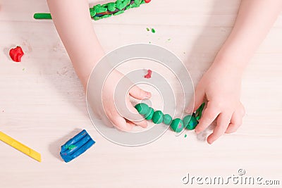 a small child sculpts from plasticine, a wooden light table Stock Photo