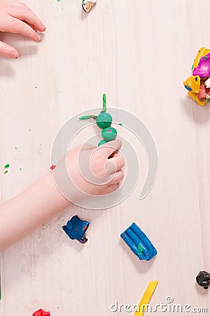 a small child sculpts from plasticine, a wooden light table Stock Photo