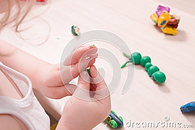 a small child sculpts from plasticine on a wooden table, the development of fine motor skills of hands Stock Photo