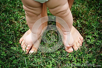 A small child stands on his father`s feet on the lawn Stock Photo