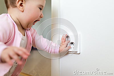 Small child touches an electrical outlet at home. Safety of children Stock Photo