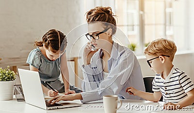 Small children being bored beside tired adult woman working on laptop at home Stock Photo