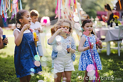 Small children outdoors in garden in summer, playing with bubbles. Stock Photo