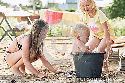 Small children play in the sand in the yard of their house in the summer. Stock Photo