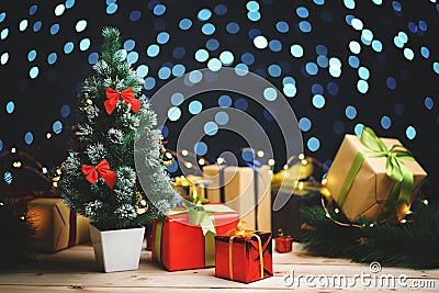 Small Christmas Tree Between Christmas Presents Against Beautifull Blue Lights Bokeh Stock Photo