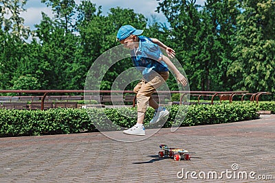 A small city boy and a skateboard. A young guy is riding in a park on a skateboard. City Style. City children. A child learns to Stock Photo