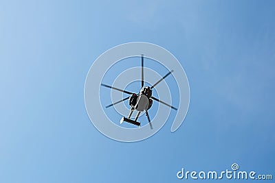 Small civil helicopter flies against a blue sky with clouds background Stock Photo