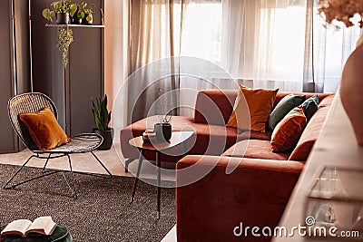 Coffee table in front of comfortable corner sofa in autumn colored living room interior Stock Photo