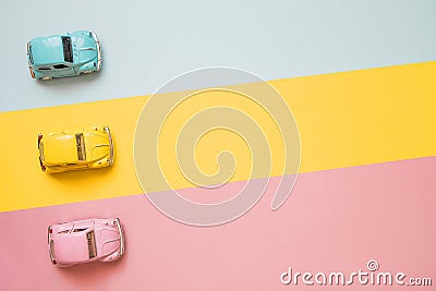 Small color toy cars at the start on a yellow, pink and blue background. Racing cars on a table top racetrack Stock Photo