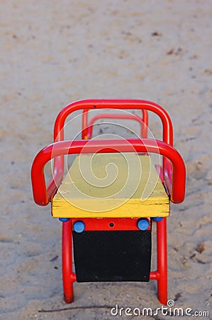 Small colorful wooden seesaw in a park surrounded by the sand under the sunlight Stock Photo