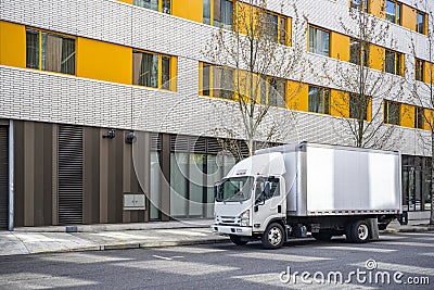 Small compact cab over truck with box trailer delivering cargo to multilevel urban city apartments Stock Photo