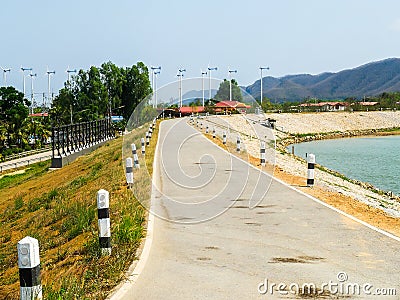 Small Curved Country Road by The Lake to The Mountain Stock Photo