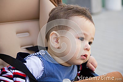 Small cute newborn baby boy sitting in a carriage in warm winter clothes with pacifier, concept of mothering autumn beanie, walk Stock Photo