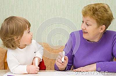 Small cute painting girl with grandma Stock Photo