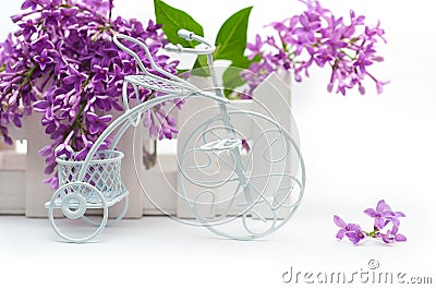 Small decorative white bicycle on a background of purple flowers lilac Stock Photo