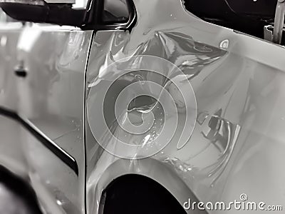 A small dent in the fender of a white metallic European car Stock Photo