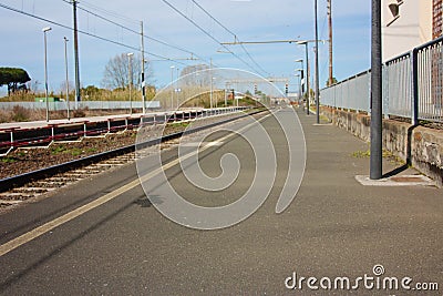 A small deserted local station during the day. sidewalk for waiting passengers waiting for trains for their journeys, between Stock Photo