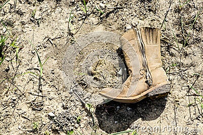 Small dirty western cowboy boot on dry ground Stock Photo