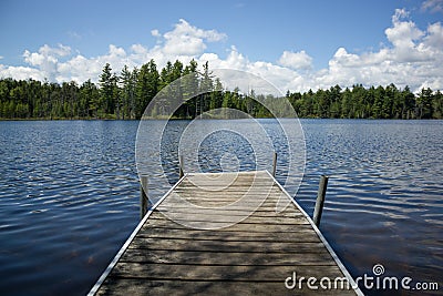 Small Dock On Beautiful Blue Pond In The Forest Stock Photo