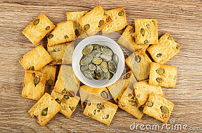 Small dry cookies with pumpkin seeds, bowl with peeled pumpkin seeds on table. Top view Stock Photo
