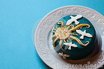 Small easter blue cake with yellow sun and white doves in the white plate. Blue background. Stock Photo