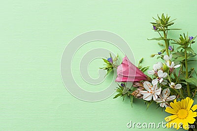Small elegant bouquet of garden and field flowers green twigs on light turquoise chartreuse background. Easter Stock Photo