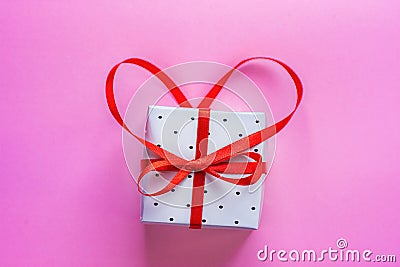 Small Elegant Gift Box Tied with Red Ribbon with Bow in Heart Shape on Pink Background. Valentine Greeting Card Wedding Stock Photo