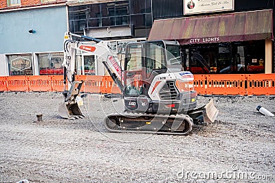 small excavator on a gravel road during street repair work in an urban environment Editorial Stock Photo