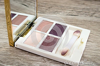 Small eyeshadow palette with a mirror on a wooden background. Stock Photo