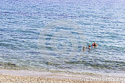 Small family swimming in the clear blue sea at Plomari in Lesvos Editorial Stock Photo